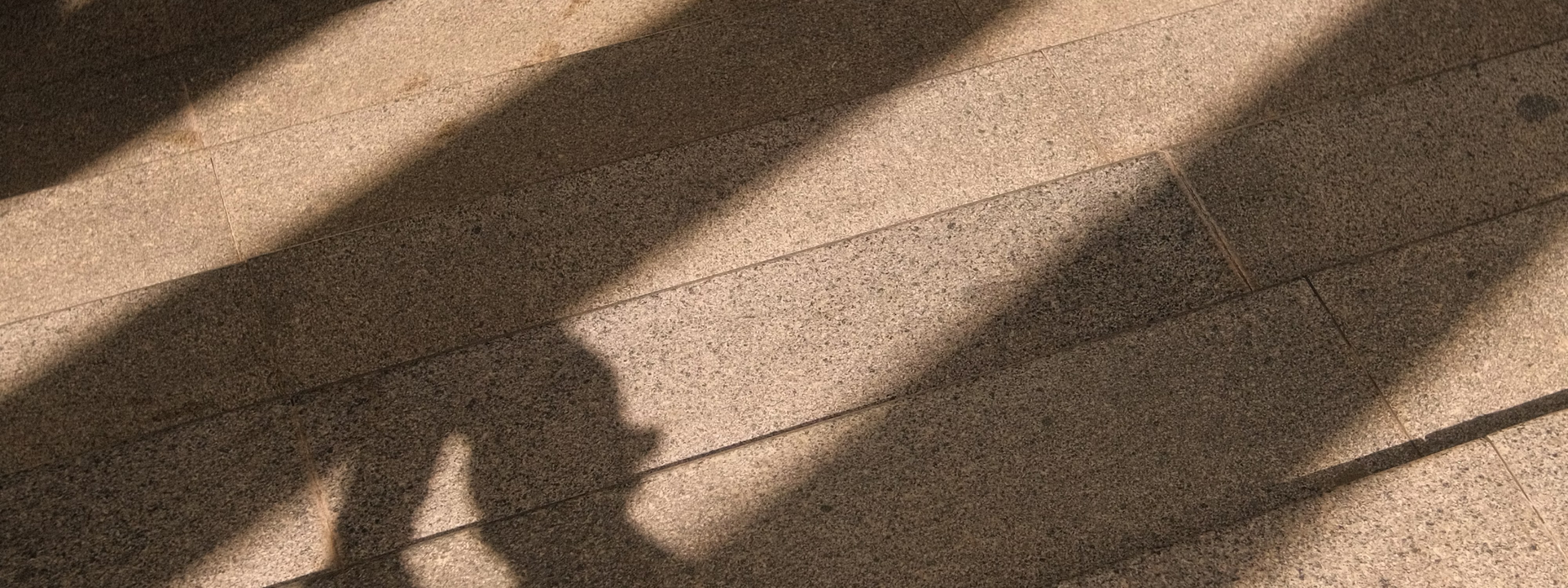 Sunlight casting shadows on textured floor with geometric patterns and lines