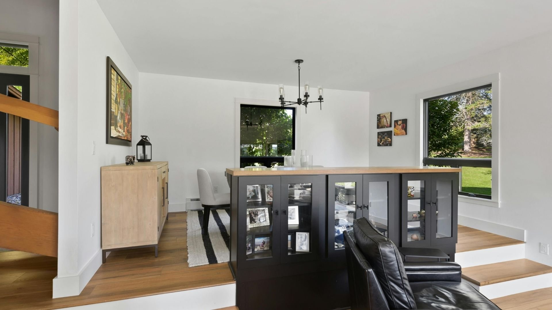 Modern open-concept kitchen and dining area with dark cabinetry, wood floors, and views to garden