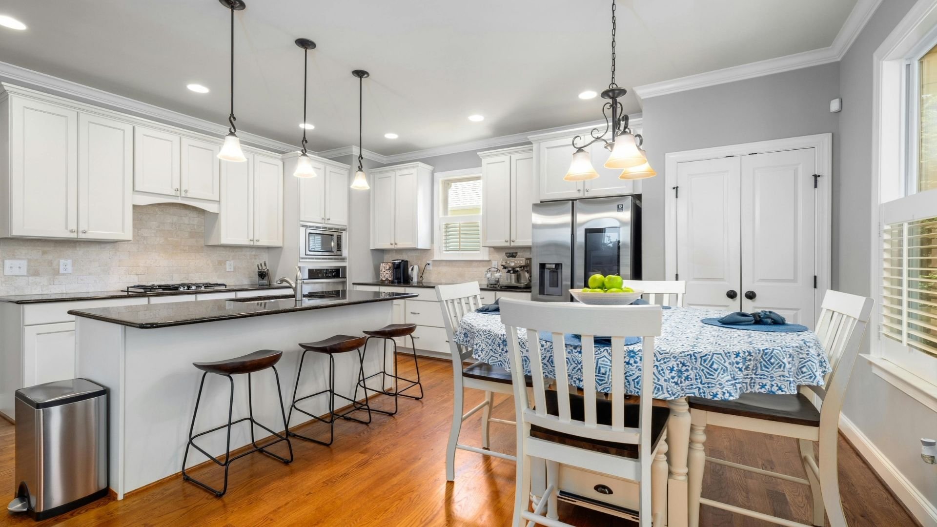 Modern kitchen-dining space with white cabinetry, stainless steel appliances, and pendant lighting